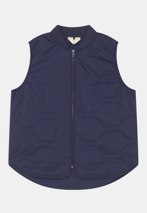 Mørkeblå quiltet vest med rund halsudskæring, lynlåslukning og buet kant. Har glat tekstur og et subtilt bølgemønster på tværs af stoffet.