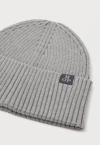 Γκρίζο πλεκτό σκουφάκι με ραβδωτή υφή, διπλωμένο τελείωμα και ορθογώνια ετικέτα με τα γράμματα "MOP" σε άσπρο χρώμα σε μαύρο φόντο.