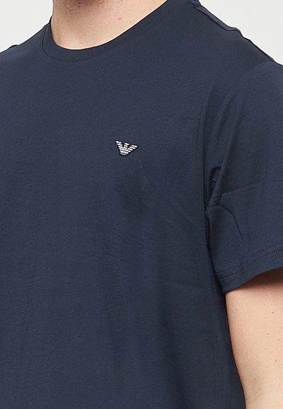 T-shirt à manches courtes bleu marine en coton doux, avec un petit logo triangulaire texturé sur la poitrine gauche.