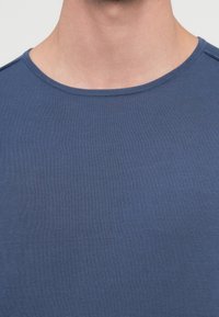 Niebieska, krótka koszulka z krótkim rękawem i okrągłym dekoltem, wykonana z fakturowanej tkaniny. Charakteryzuje się delikatnym prążkowanym wzorem i czystym, minimalistycznym designem.