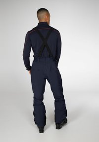Marine ski-broek met verstelbare zwarte bretels, aansluitend bij de taille en met wijde pijpen, gemaakt van duurzaam, waterafstotend materiaal.