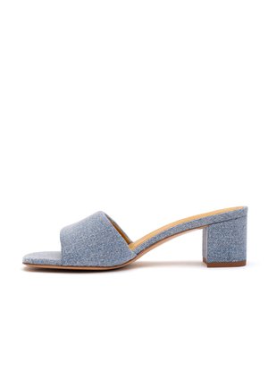 Mule open-toe in denim azzurro chiaro con cinturino largo e tacco largo di media altezza, mostrata di profilo su sfondo bianco.