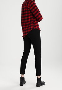 Röd och svart rutig flanellskjorta med långa ärmar, i kombination med slim-fit svarta jeans och svarta ankelstövlar. Enkel, avslappnad outfit.