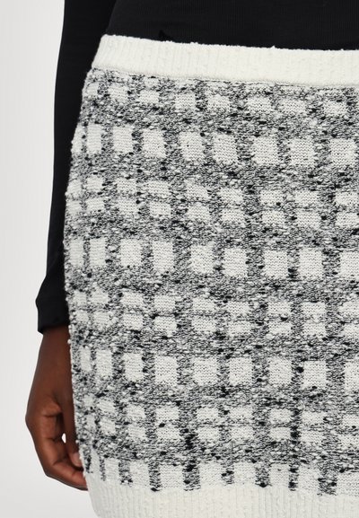Knit skirt featuring a black and white checkered pattern, textured surface, and a ribbed white waistband for added detail.