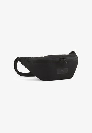 Schwarze Stoffbauchtasche mit geschwungener Form, Reißverschlussverschluss, verstellbarem Gurt und einem kleinen Markenpatch auf der Vorderseite.