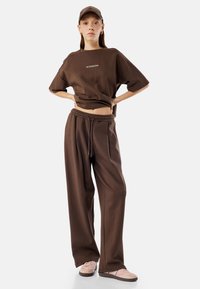 Brun oversized t-shirt med teksten "NO EXCUSES EVER", parret med matchende brune sweatpants. Blødt stof, afslappet pasform og et casual look.