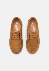 Ruske suède čevlje z okroglimi prsti, zasnovo na vezanje, belimi šivi in teksturiranim gumijastim podplatom. Blagovna znamka vidna na notranjih podplatih.