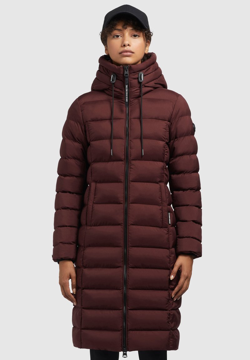 Manteau long matelassé bordeaux avec un col haut, une capuche à cordon, une fermeture éclair pleine longueur et des poches latérales. Texture lisse et silhouette ajustée.