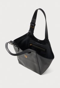 Mala de mão em pele preta com um formato estruturado, apresentando uma única alça ajustável, um bolso com fecho interior e um detalhe em logo dourado.