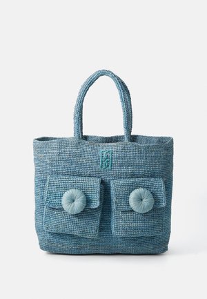 Blue woven tote bag with two front pockets and button-like accents. Features sturdy handles, textured surface, and a stitched logo at the top.