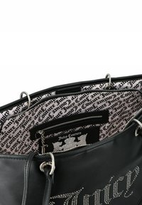 Zwarte Juicy Couture handtas met zilveren studs die de merknaam spellen, binnenzak met rits en een gedrukte stoffen voering.