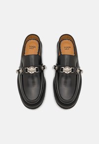 Mocasini din piele neagră cu un finisaj lucios, având o curea decorativă din lanț argintiu și o branț de culoare maro în contrast. Talpă texturată pentru aderență.