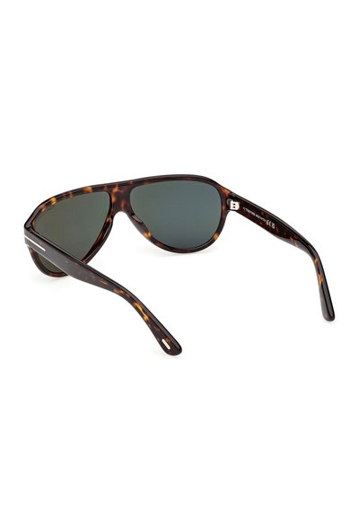 Lunettes de soleil avec monture écaille de tortue, verres ovales foncés, branches légèrement courbées et un accent argenté près des charnières sur fond blanc.
