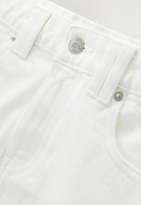 Shorts en denim blanc avec une taille structurée, détail de bouton en argent et tissu texturé. Caractéristiques : poches avant et couture soignée.
