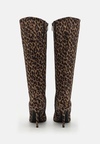 Bottes montantes en tissu imprimé léopard, avec un design élégant, des talons pointus et des fermetures éclairs à l'arrière pour un enfilage facile.