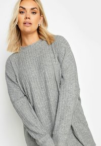Hellgrauer, rippierter Pullover mit runder Ausschnitt und langen Ärmeln; verfügt über eine dezente Textur und seitliche Schlitze für zusätzliche Details.