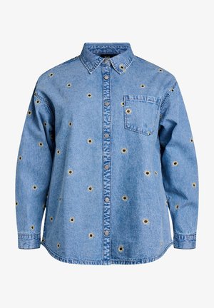 Heled sinine teksajakk pikade varrukatega, nööbid ees ja rinnaeemel. Omab ümmargusi lillemotiive mustade keskmikega.