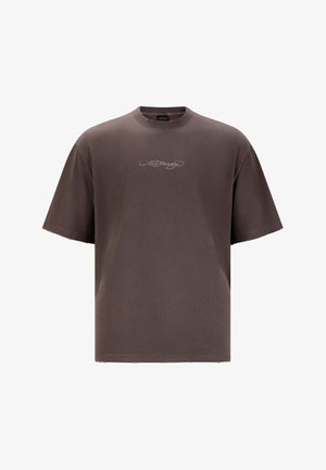 Brun oversized t-shirt i blødt stof, med rund hals og kortærmede ærmer. Lille hvid signaturlogo broderet på brystet.