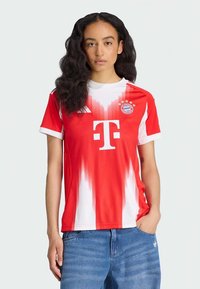 Koszulka Bayern Monachium z krótkim rękawem w kolorach czerwonym i białym, z gradientowym wzorem, okrągłym kołnierzem i logo drużyny. Materiał wydaje się lekki i gładki.