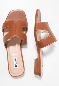 Tan leather slide sandals with square toe, two wide straps featuring cutouts, and a low block heel. Contrast stitching details.