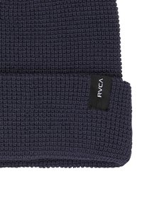 Granatowa czapka beanie o teksturowanym wzorze waflowym, z podwiniętym mankietem i czarną prostokątną metką marki wszytą z boku.