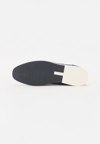 Navy shoe with a textured fabric upper, round toe, and a white rubber sole. Features a flat design with a smooth transition at the heel.