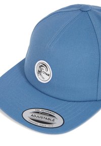 Blå kasket med justerbar snapback-design. Har et cirkulært sort og hvidt logo samt en sølvmærkat med teksten "The Authentic Adjustable."