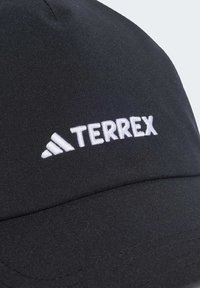 Gorra negra de tela suave con el logo blanco "TERREX" bordado en la parte frontal, con visera curvada y detalles cosidos.