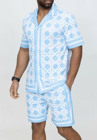 Chemise à manches courtes avec boutons et un short assorti en bleu clair avec des motifs géométriques blancs, comportant des accents rayés le long des manches.
