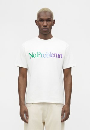 Ung mand med kort blegnet hår iført en hvid t-shirt med teksten "No Problemo" i grøn, blå og lilla, stående mod en ensfarvet hvid baggrund.