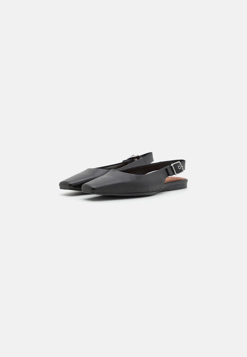 Zapatos slingback negros con punta afilada, textura de cuero suave y un sutil detalle de hebilla en la correa del tobillo. Tacón bajo y plano.