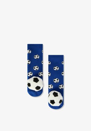 Chaussettes bleues avec petits motifs de ballons de football noirs et blancs et grandes décorations en forme de ballons de football duveteux sur les orteils.