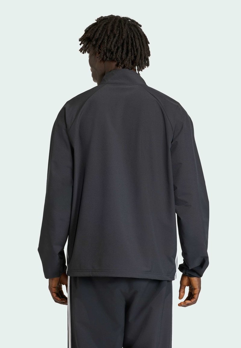 Schwarze leichte Jacke mit Stehkragen, langen Ärmeln und lockerer Passform. Strukturiertem Stoff mit subtilen Nahtdetails an den Schultern.