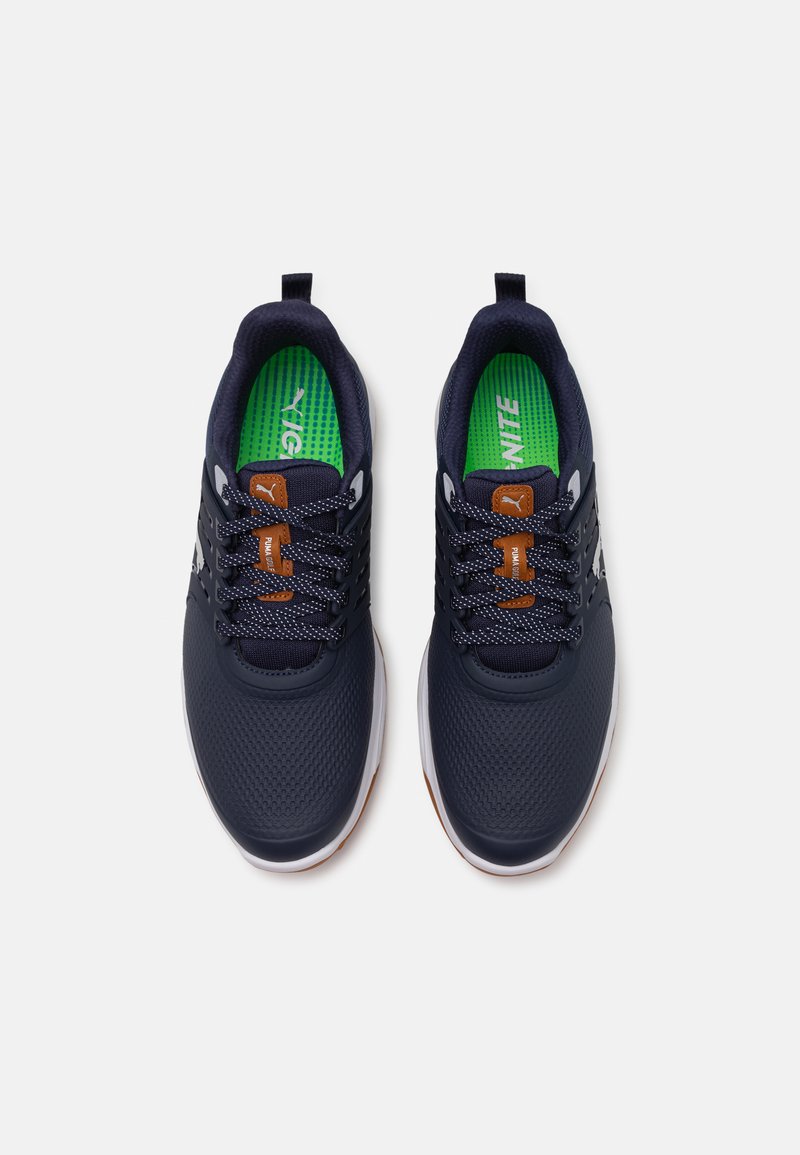 Marineblaue Sportschuhe mit Mesh-Obermaterial, kontrastierender grüner Einlegesohle und braunen Akzenten. Schnürdesign mit strukturiertem Oberflächen und weißer Sohle.