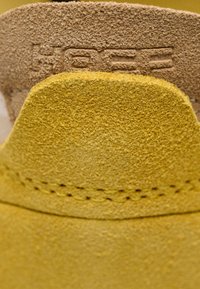 Primo piano dell'interno scarpa in pelle scamosciata testurizzata con il marchio "HÖGL" in rilievo visibile nell'area del tallone.