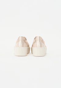 Baskets à plateforme en beige clair, avec une tige lisse ressemblant à du satin, une semelle en caoutchouc blanc texturé et des détails de couture subtils.