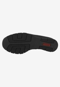 Semelle de chaussure en caoutchouc noir avec un motif texturé et deprofondes rainures pour une meilleure adhérence. Présente un logo rouge embossé sur le côté.