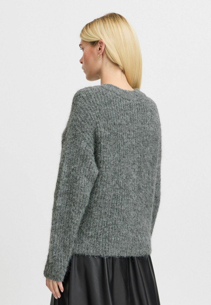 Maglione lavorato a maglia in grigio scuro, con una vestibilità ampia, maniche lunghe e un motivo testurizzato. Presenta un collo rotondo e orlo leggermente accorciato.