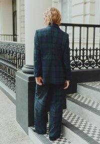 Grøn- og marineblå ternet jakkesæt med et struktureret design. Inkluderer brede bukser og en skræddersyet blazer. Glat tekstur og formel æstetik.