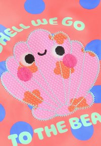 Korallitaustal on roosa, tekstuuriga kest mustade ja roosade aktsentidega, ümbritsetud siniste täppidega ja rohelise tekstiga "KAS ME LÄHEME RANDA?"