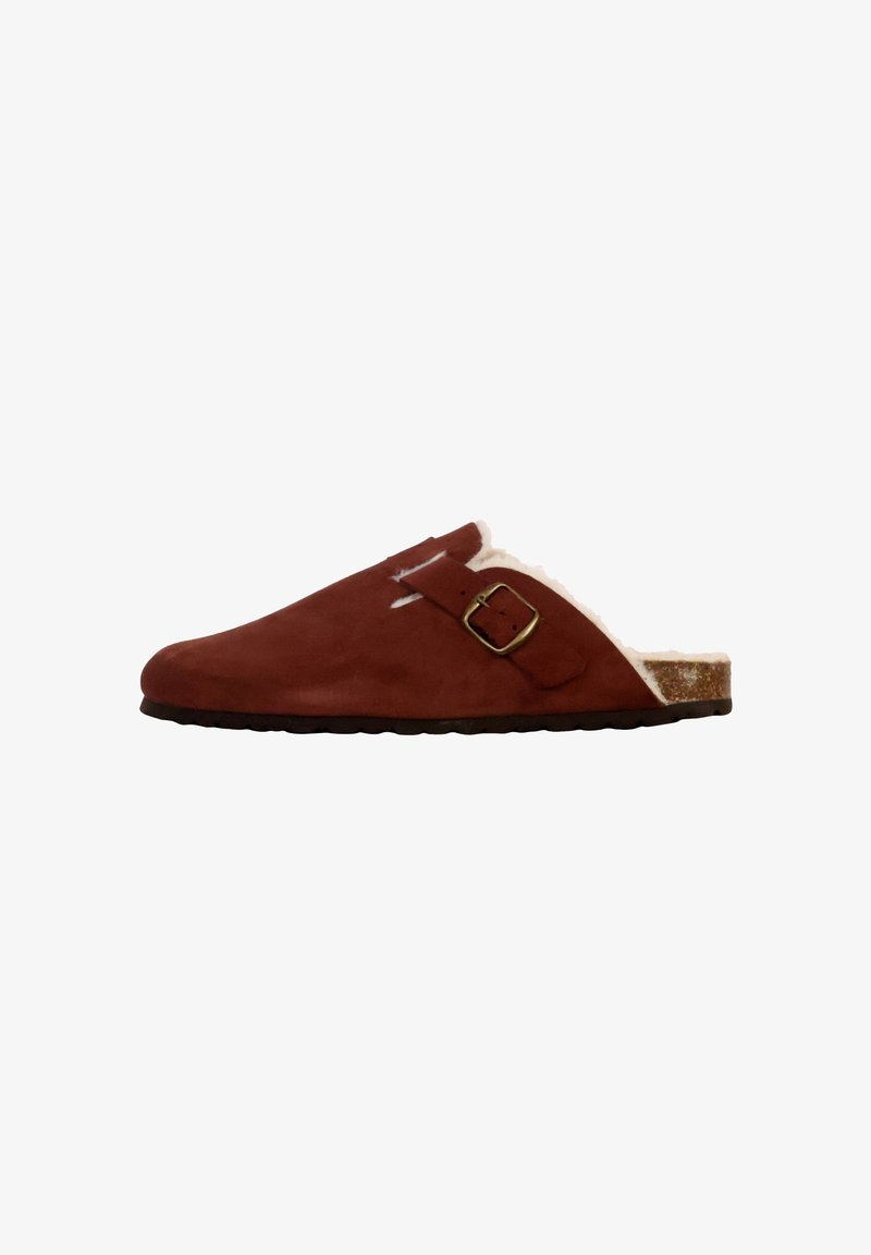 Zoccoli in suede di colore arancione bruciato con fodera in pelliccia bianca, un'apertura con fibbia in metallo e suola in gomma testurizzata. Design slip-on a profilo basso.