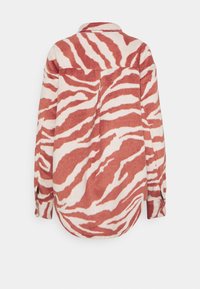 Chemise à manches longues boutonnée avec des rayures zébrées rouges et blanches, dotée d'un col et de poignets boutonnés, vue de dos.