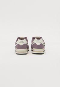 Lilla semsket sneakers med hvit aksent, utstyrt med polstret krage, logodetaljer og stripet mellomsåle for økt komfort og støtte.