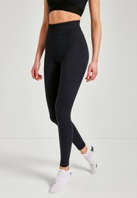 Leggings neri a vita alta realizzati in tessuto testurizzato, design aderente con un motivo geometrico e taglio alla caviglia.