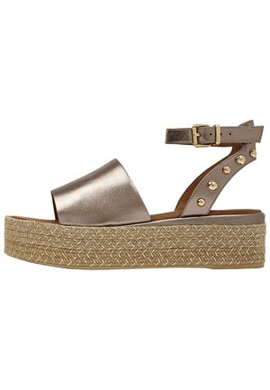 Metallic bronze platformsandal med flettet rebssål, ankelrem med guldbue og guldbeslagsdetaljer på hælremmen.