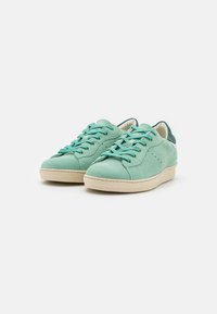 Sneaker verde menta chiaro con tomaia in suede, chiusura con lacci, suola in gomma beige e accentuazione del tallone in verde scuro a contrasto.