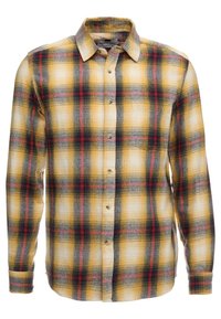 Camicia a quadri con una base gialla e accenti neri, rossi e grigi. Maniche lunghe, chiusura con bottoni e un classico design del colletto.