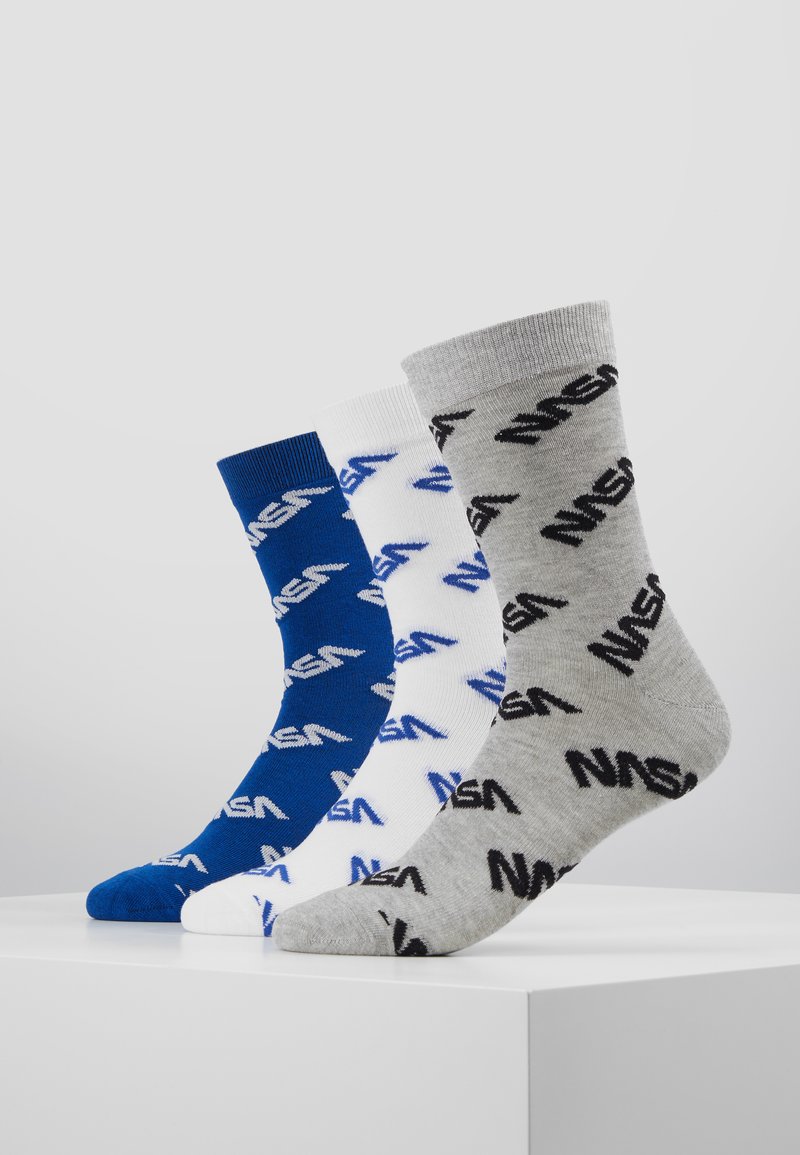 Trois paires de chaussettes : bleu marine, blanc et gris, chacune avec un motif de logo NASA noir. Mélange de coton avec des bords côtelés, longueur mi-mollet décontractée.