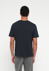 Tumesinine lühikeste varrukatega T-särk puuvillase kangaga, ümara kaelusega, sirge lõike ja minimalistliku disainiga, sileda tekstuuriga.