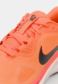 Nike-Laufschuh in leuchtendem Korallenpink mit Netzüberzug, schwarzem Swoosh, flachen Schnürsenkeln und strukturierten Akzenten auf dem Obermaterial und der Zwischensohle.